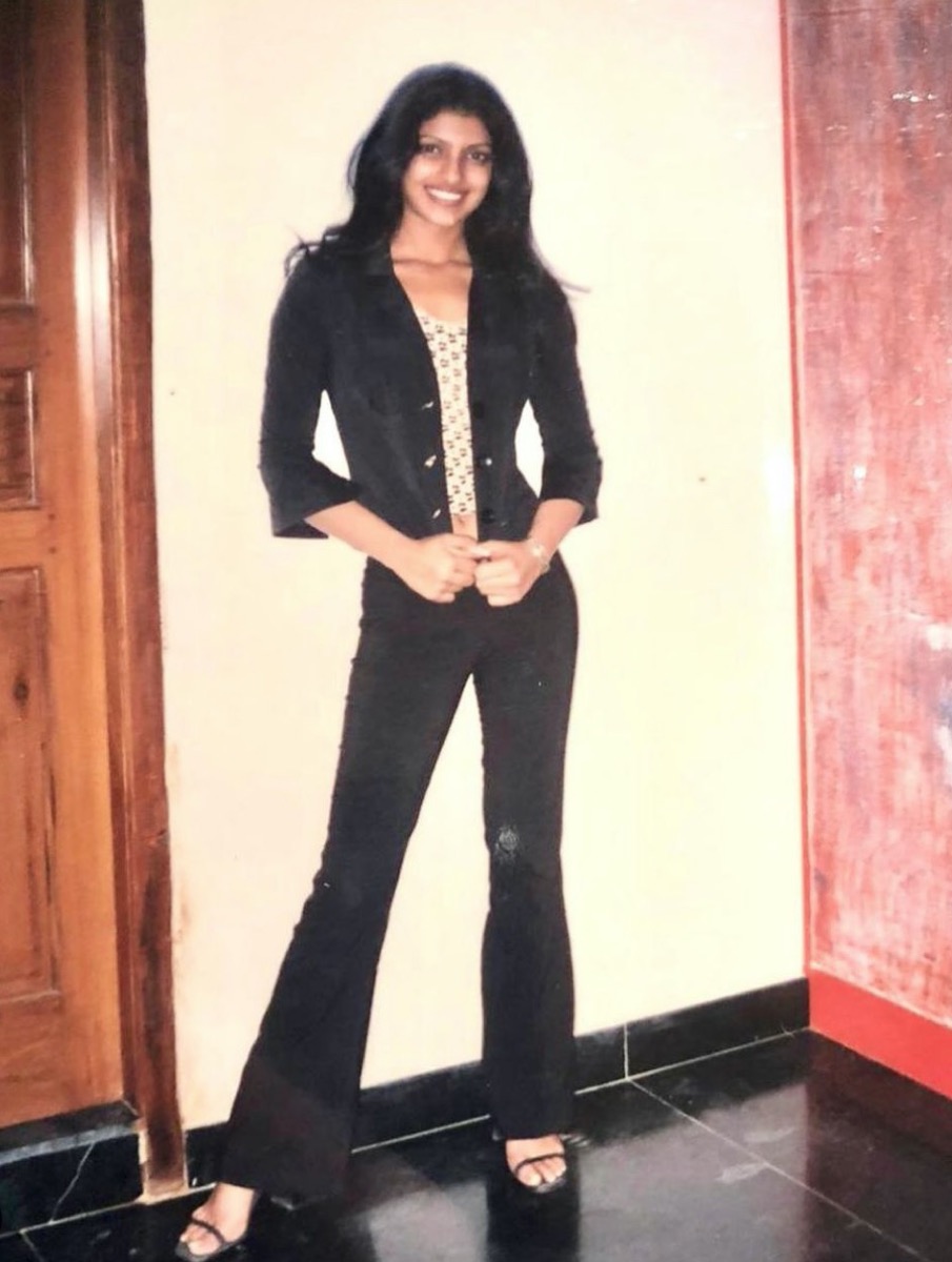 teenage priyanka chopra in a black bell bottom outfit standing against white wall