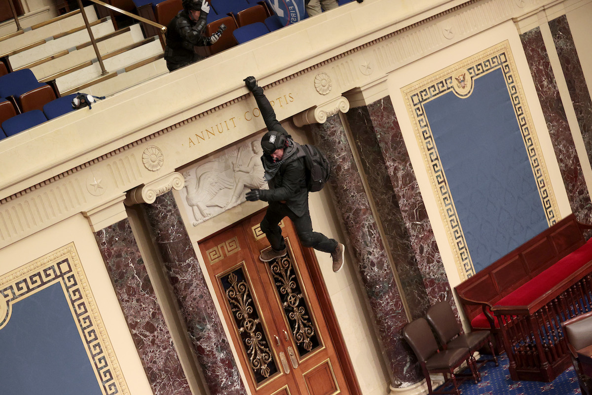 A protester is seen hanging from the balcony in the Senate Chamber on January 06, 2021 in Washington, DC. Congress held a joint session today to ratify President-elect Joe Biden's 306-232 Electoral College win over President Donald Trump. Pro-Trump protesters have entered the U.S.