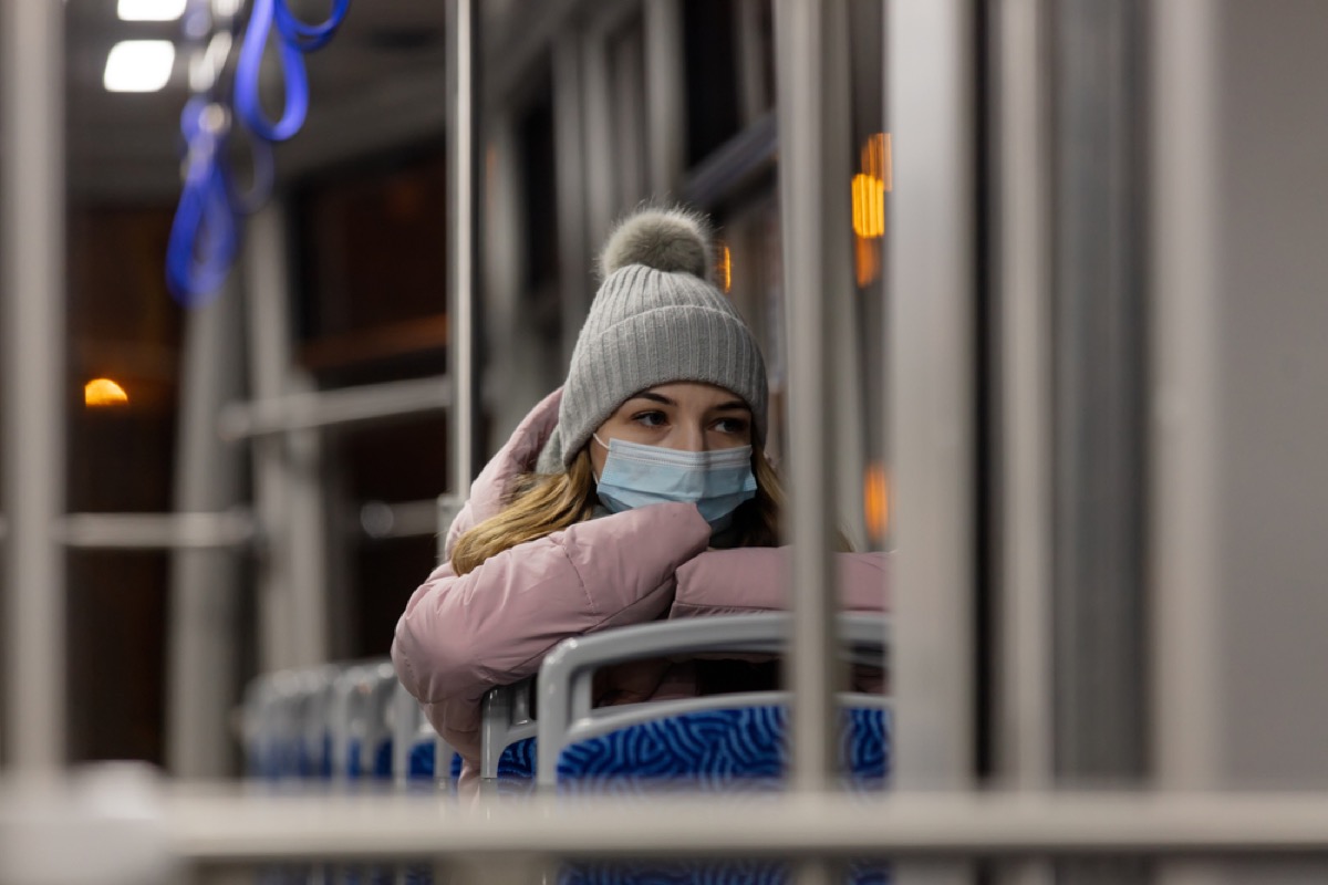 woman in winter clothing and face mask on a bus