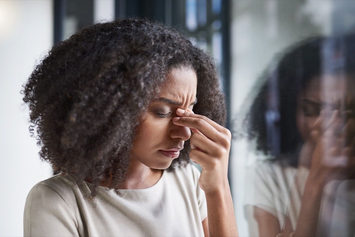 彼女のオフィスに立っている間に頭痛に苦しんでいる魅力的な若い実業家のトリミングショット