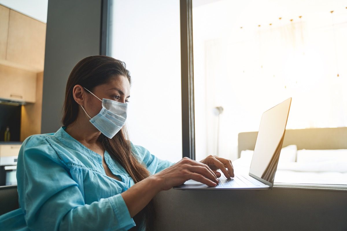 Focused serious dark-haired young female freelancer under quarantine working on her computer at home