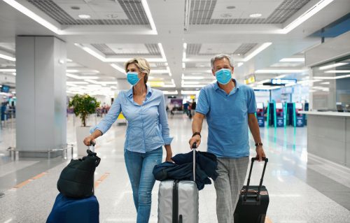 Closeup front view of a middle aged couple waiting for a flight amid coronavirus while wearing masks