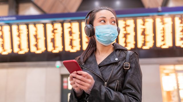 Woman wearing face mask at airport and maintaining social distance