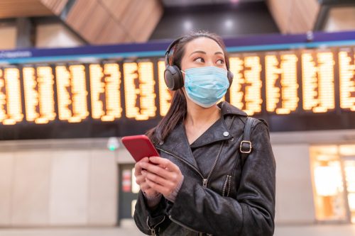 Woman wearing face mask at airport and maintaining social distance