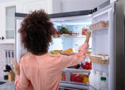 woman in pink shirt with dark curly hair opening double door fridge