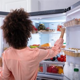 woman in pink shirt with dark curly hair opening double door fridge