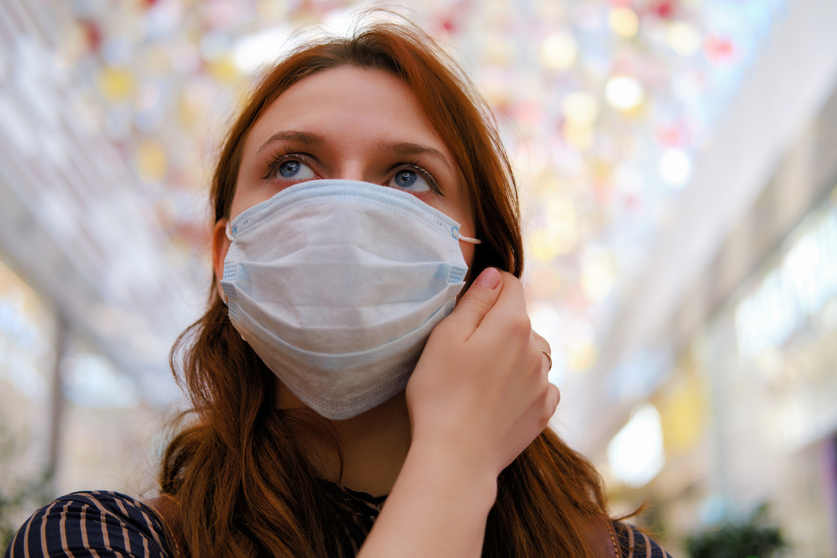 A young woman is considering whether to remove the medical mask after the end of the quarantine due to the coronavirus