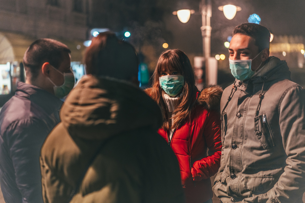 Group of young people with masks talking on street.