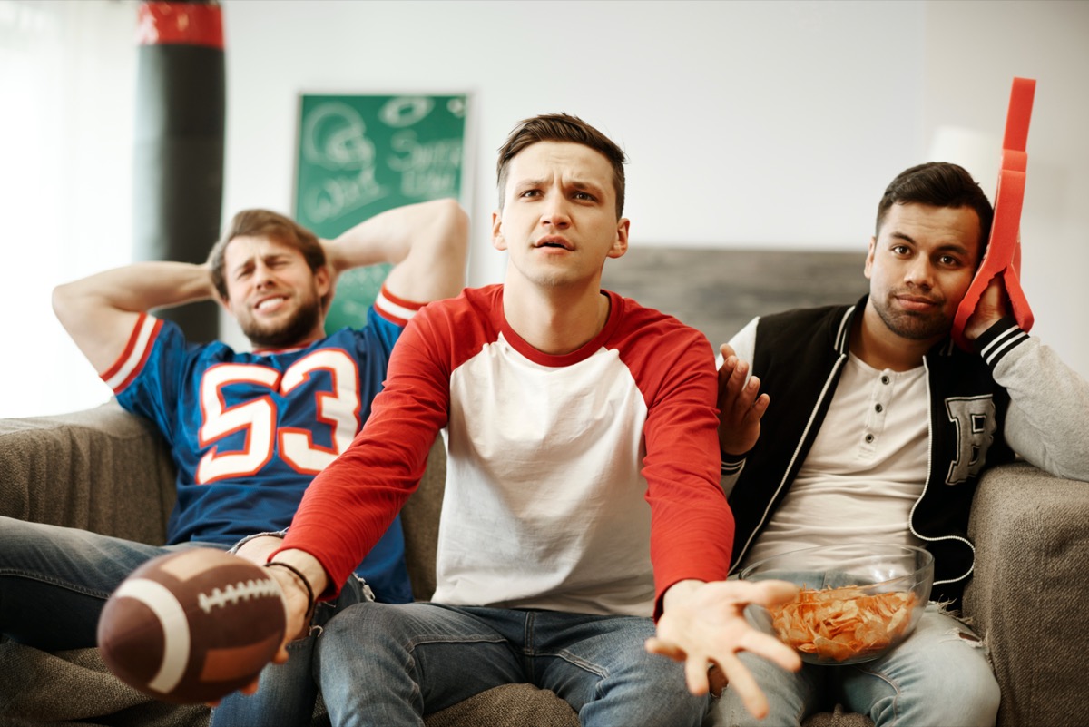 Three male friends watching their favorite football team lose