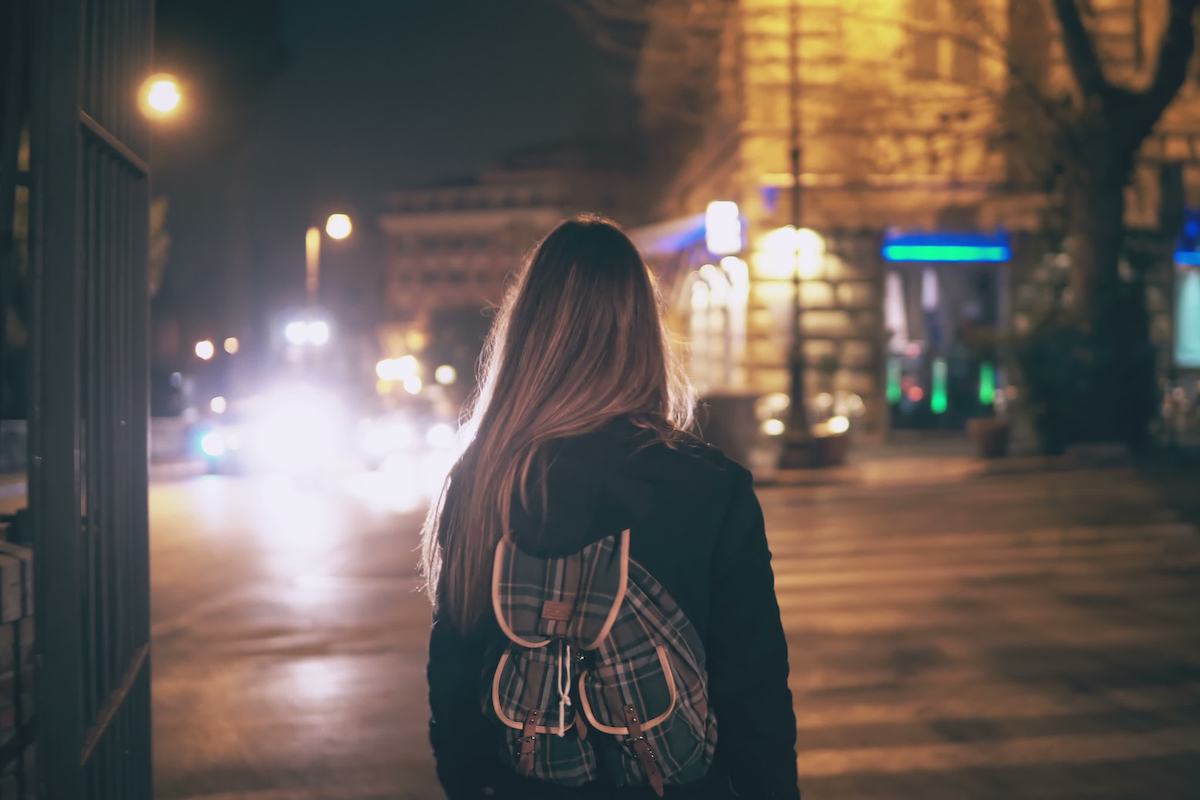 Rückansicht einer jungen Frau, die spät nachts im Stadtzentrum spazieren geht