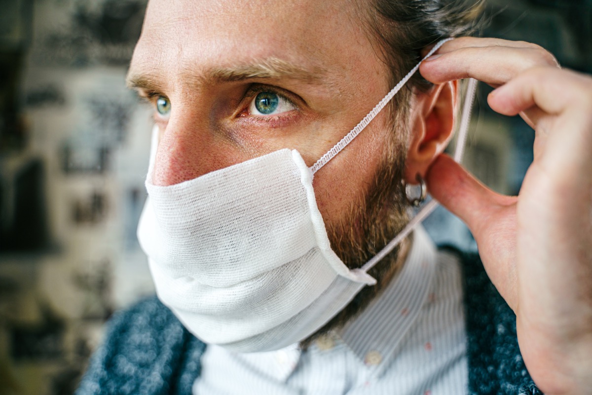 young bearded man putting on mask