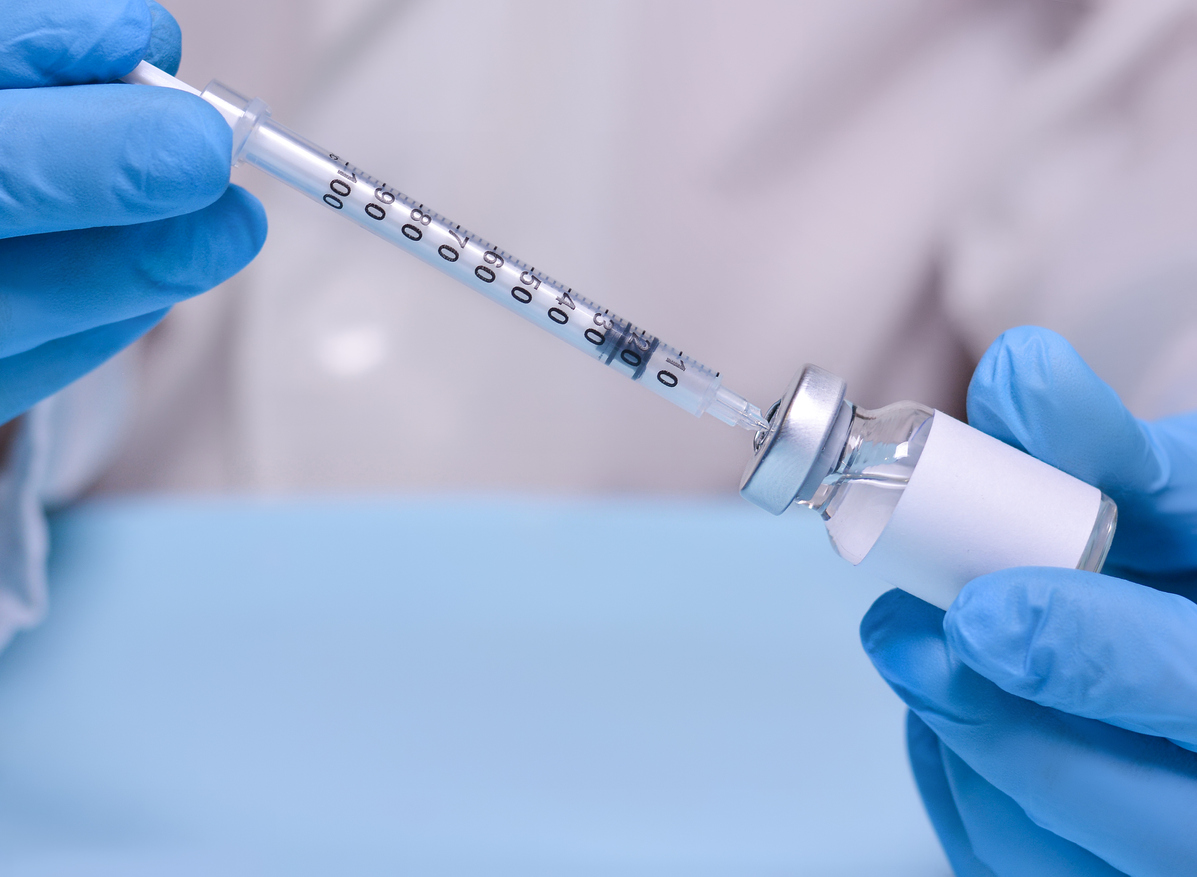 A doctor wearing gloves fills a syringe with COVID-19 vaccine