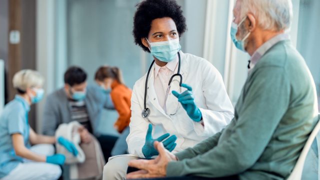 young doctor treating senior male wearing a surgical mask