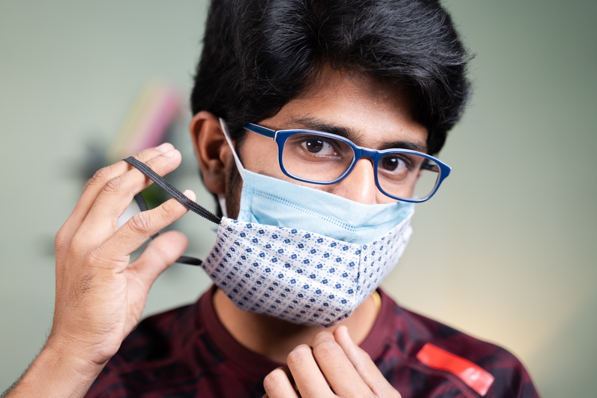 Young man wearing double or two face mask to protect from coronavirus or covid-19 outbreak - concept of safety, healthcare, medical and hygiene.