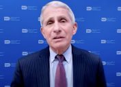 dr anthony fauci in purple or brown tie and suit in front of blue background