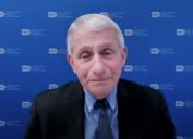 dr anthony fauci in front of a blue background wearing a blue shirt and black suit