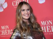 elle macpherson in a shiny gold dress in front of a red step-and-repeat
