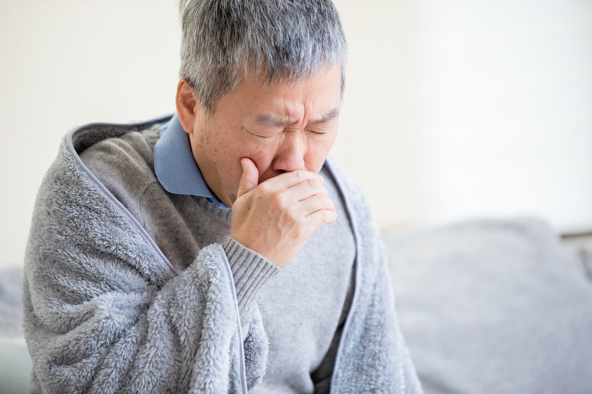 Elderly sick man has a cough at home