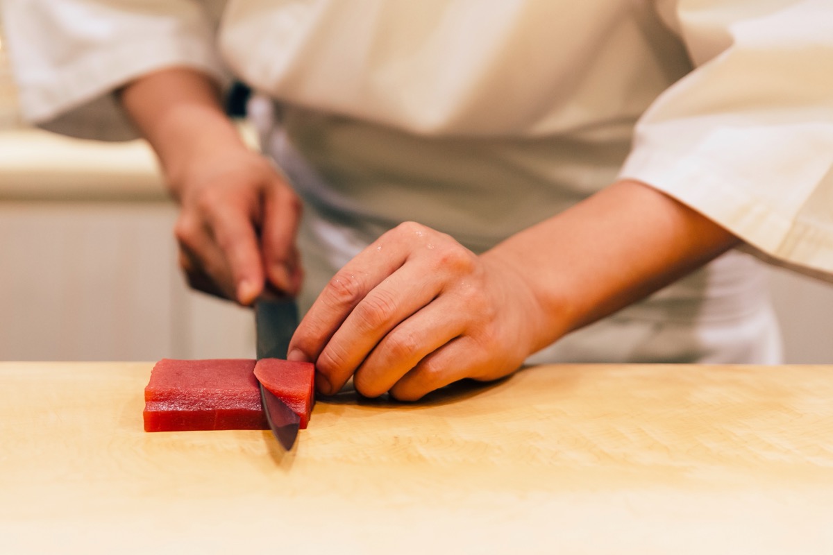man cutting tuna steak with knife