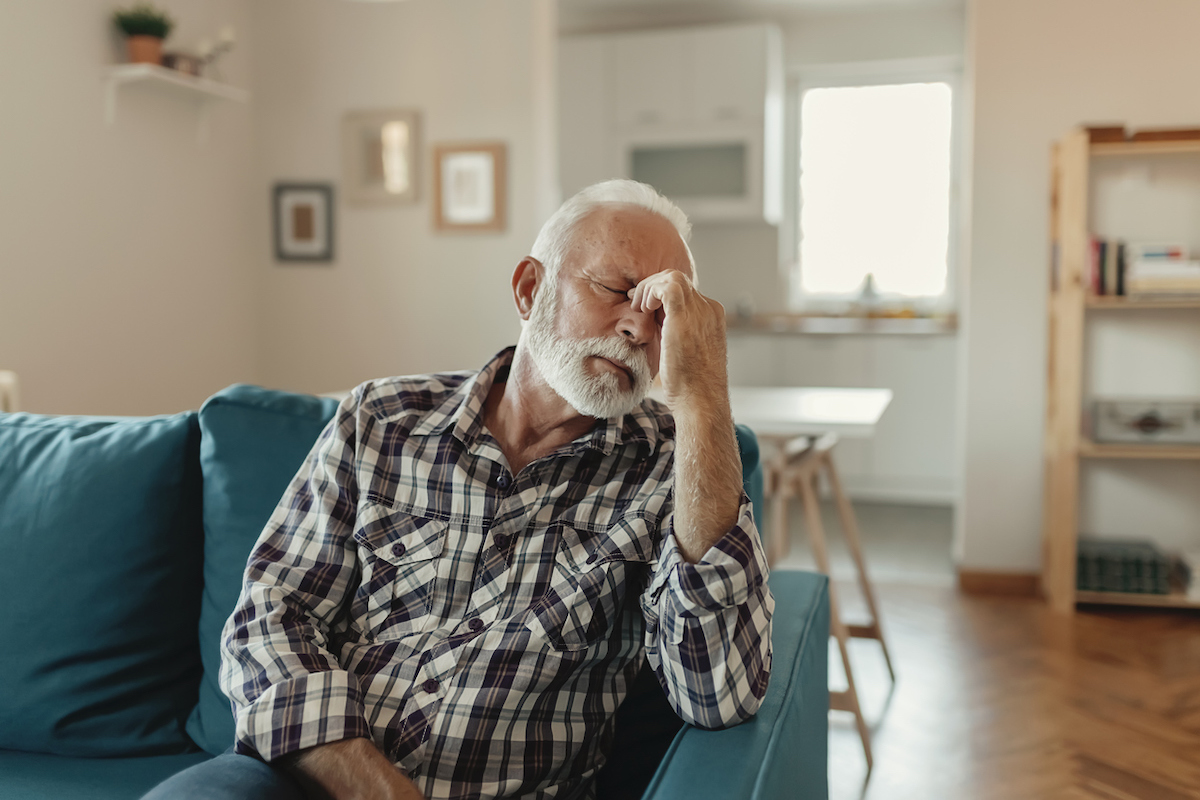 Senior Man Suffering From a headache While Sitting on the sofa in the Living Room