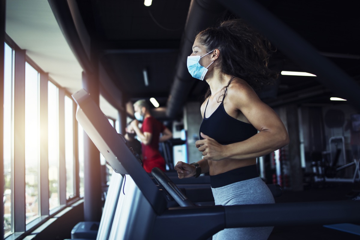 Active fitness woman wearing hygienic protective face mask while training in gym to protect herself and others against coronavirus or covid-19. Stay safe and healthy.
