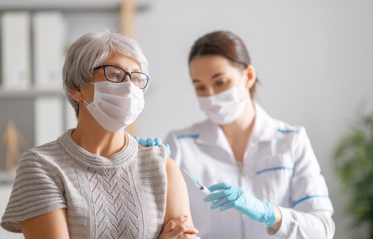 gray haired woman getting a covid vaccine from young female doctor