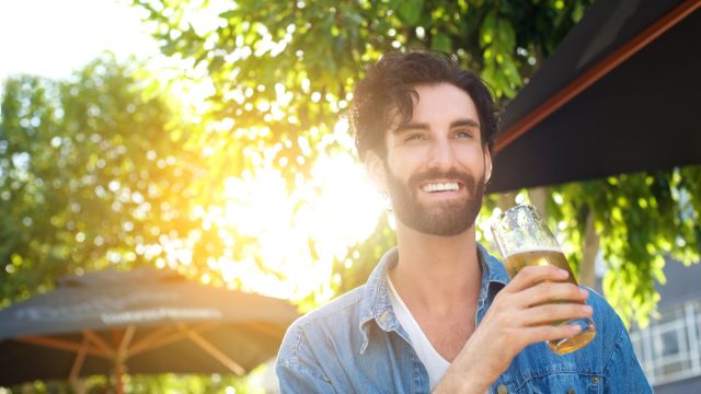 Man smiling drinking outside