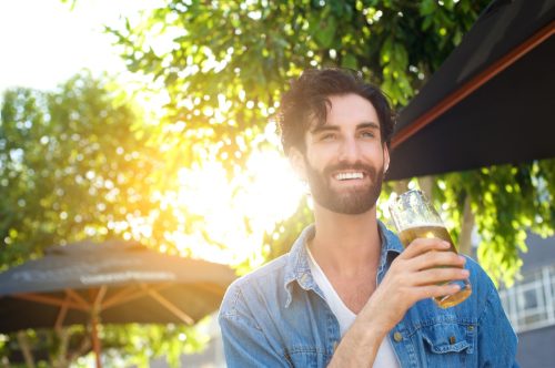 Man smiling drinking outside