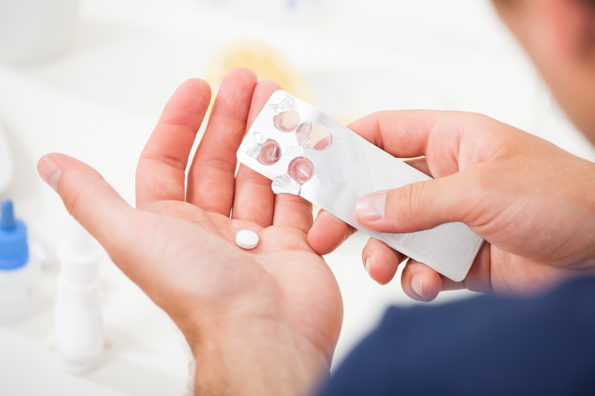 person removing pill from medication blister pack into hand