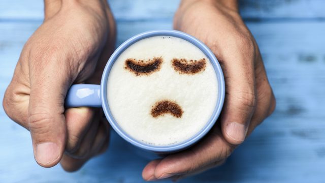 Man with a cup of cappuccino with a sad face