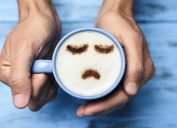 Man with a cup of cappuccino with a sad face