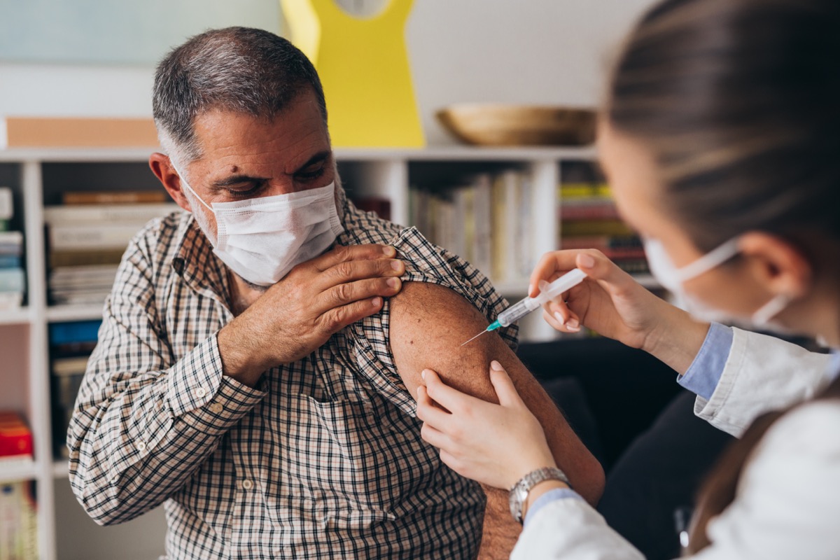 man pulling up his shirt on arm, getting COVID vaccin
