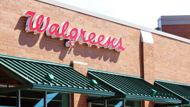 The storefront of a Walgreens pharmacy with red lettering and a green awning
