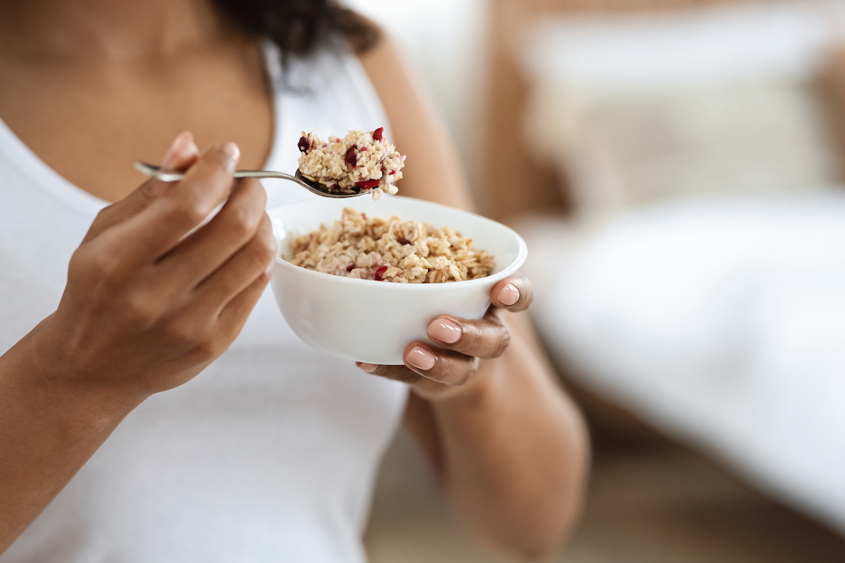 Portrait of woman eating oatmeal with fruits for breakfast