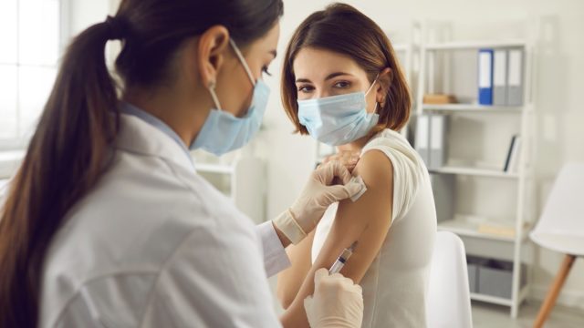 woman getting covid vaccine wearing a surgical mask