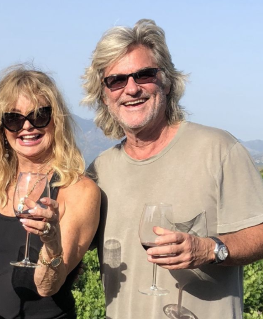 Goldie Hawn and Kurt Russell posing while holding wine glasses
