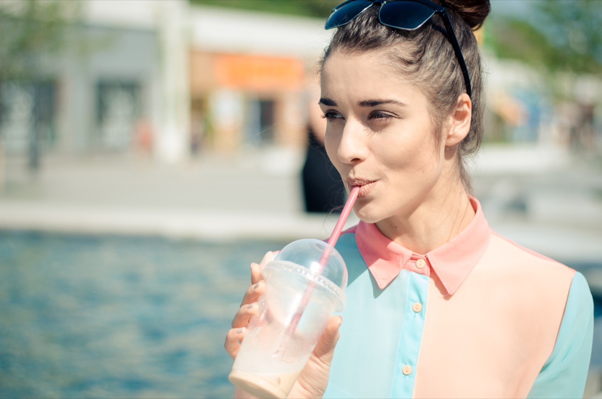 Young woman drinking iced coffee sunny day