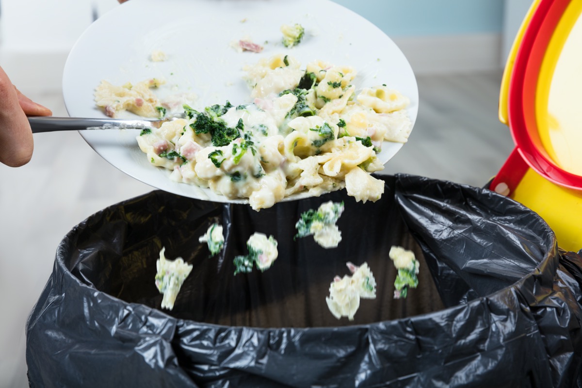 Person throwing leftover pasta into the garbage