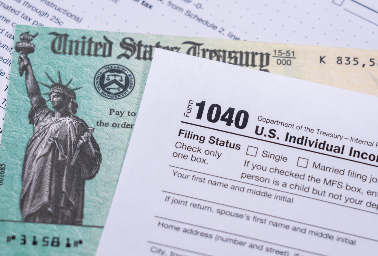 A stimulus check sitting underneath a 1040 tax form