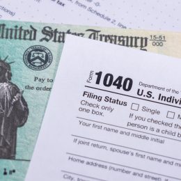 A stimulus check sitting underneath a 1040 tax form