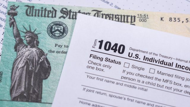 A stimulus check sitting underneath a 1040 tax form
