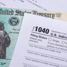 A stimulus check sitting underneath a 1040 tax form