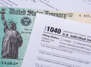 A stimulus check sitting underneath a 1040 tax form