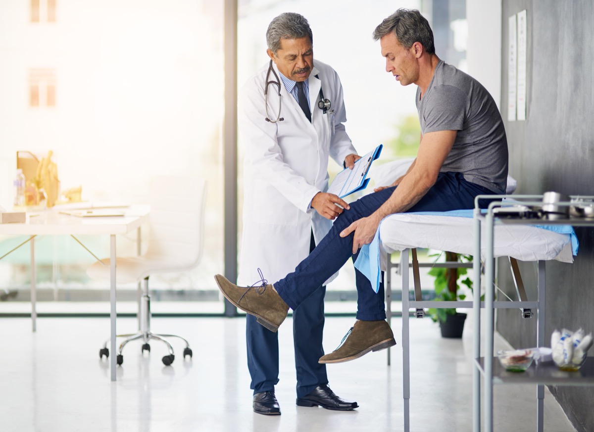 Кадър на зрял лекар, който преглежда своя пациент, който е загрижен за коляното си