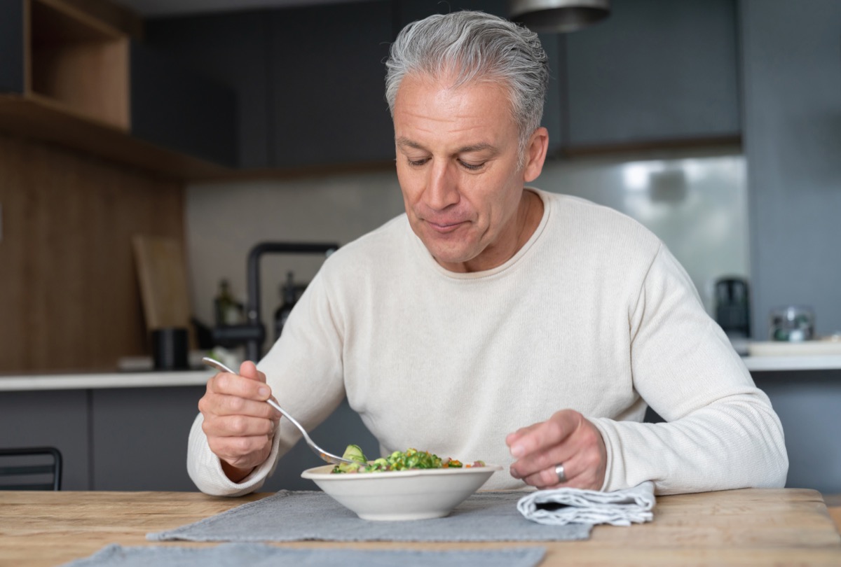 Portrait of a happy man at home eating a healthy salad – nutrition concepts