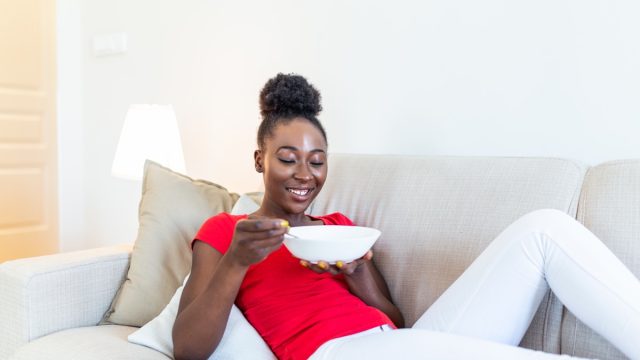 Woman eating out of a bowl on the couch