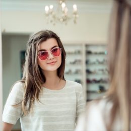 young woman with brown hair trying on sunglasses