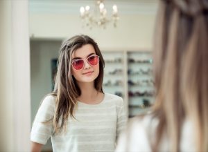 young woman with brown hair trying on sunglasses
