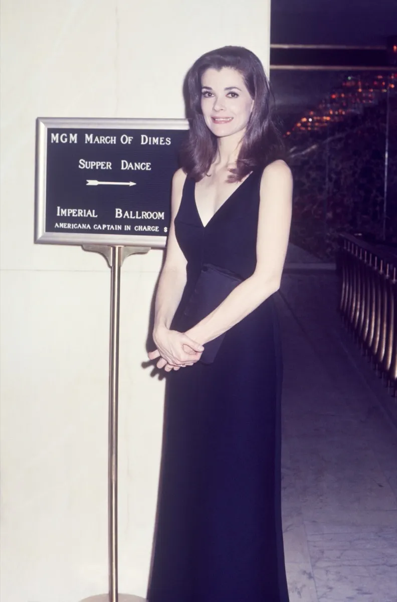 jessica walter standing next to a sign about a march of dimes dinner in a black dress