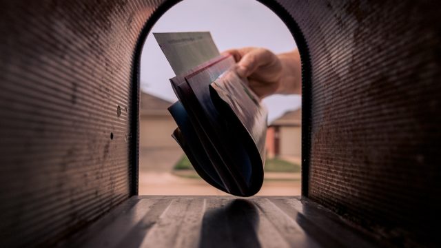 A hand removing mail from the mailbox.